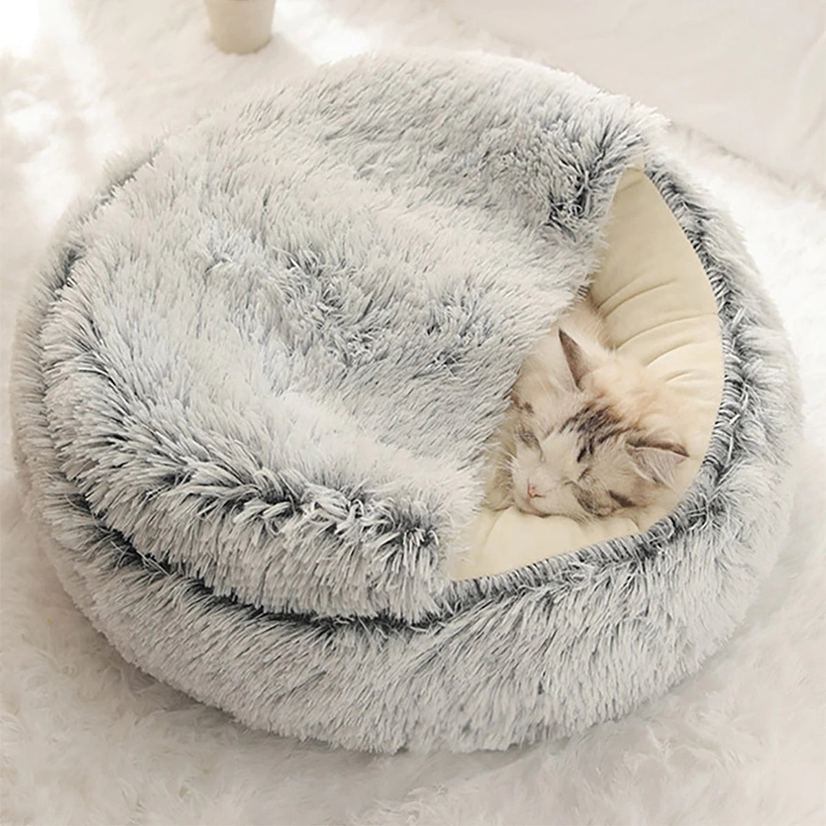 A cat sleeping soundly in a round, plush cat bed with a cave-like entrance, providing a cozy and secure den for relaxation and comfort.